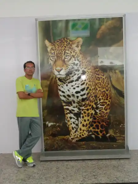 Mauricio Bezerra de Sousa ao lado de um painel com uma onça-pintada no aeroporto de Manaus